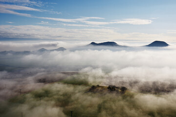 Foggy misty autumn fall morning in Czech Central Mountains, hills above inversion layers and...