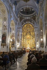 Seville, Spain - Mar 23, 2025: Walking in Seville. Real Parroquia de Santa Maria Magdalena. Streets, buildings. Lifestyle in the urban area. Cloudy spring day. Selective focus