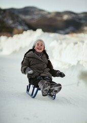 A girl laughs while sledding in winter