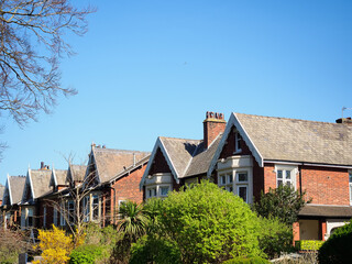 Row of charming red brick houses with gabled roofs under a clear blue sky.