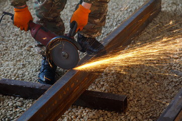 A man is cutting a piece of metal with a saw