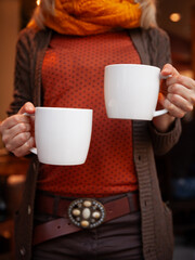 The closeup of the girl's hands holding two white cups of hot coffee. Selective soft focus