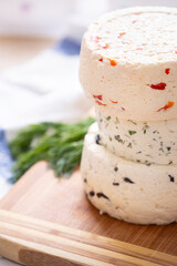 Several varieties of homemade cheese with different fillings with paprika, dill and olives on a wooden board