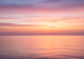 Naklejka premium Blurred Calm Sunset Over Ocean, Peaceful Skies, Serene Waterscape, Pink and Orange Hues, Nature's Beauty.