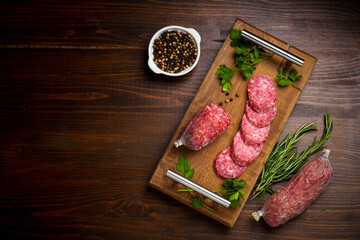 Smoked sausages, salami slices served on wooden table, flat lay