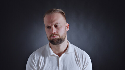 A man in a white shirt displays a frown, conveying frustration or dissatisfaction. The close-up...
