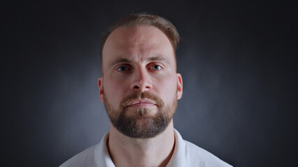 A man with a beard and serious expression poses for a close-up shot, exuding confidence and focus.