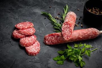 Traditional smoked salami sausage with spices. Salami sausage slices on a black background.