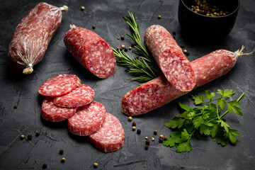 Traditional smoked salami sausage with spices. Salami sausage slices on a black background.