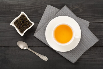 Cup of tea with dry and fresh leaves on wooden background, top view