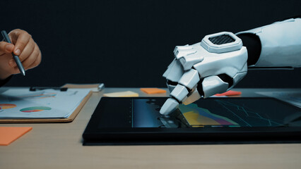 A futuristic robotic hand engages with a digital tablet showing colorful graphs in a sleek office...