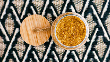 Brown granulated sugar in glass jar with patterned background
