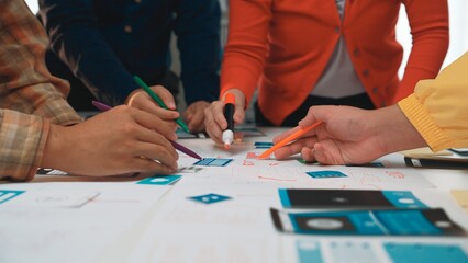 A vibrant scene of teamwork as diverse hands engage with colorful markers on design papers. The...