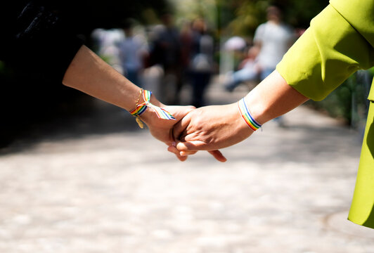 Couple holding hands showing rainbow bracelets: celebrating lgbtq+ pride and love