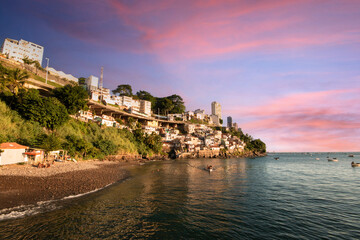 Naklejka premium Colorful hillside homes Gamboa Salvador Bahia overlook the calm sea at sunset