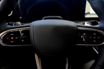 A close-up of a modern car's steering wheel with control buttons