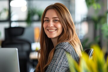 A woman with long brown hair smiles while working at a desk in an office, Celebrating the unique talents and skills you bring to our team