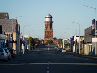 Urban city cityscape road leading to historical red brick stone Invercargill water tower storage...