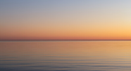 Obraz premium Calm ocean at sunrise with clear sky and horizon line