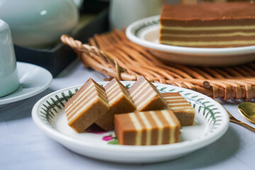A traditional steamed layer cake with alternating vibrant layers, showcasing a soft, moist texture...