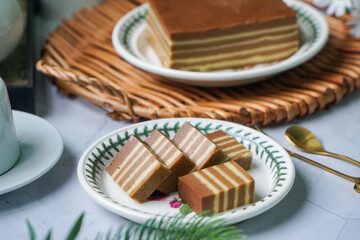 A traditional Indonesian steamed layer cake with alternating vibrant layers, showcasing a soft,...