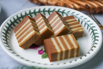 A traditional Indonesian steamed layer cake with alternating vibrant layers, showcasing a soft,...