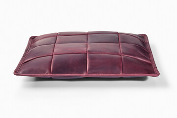 Burgundy leather cushion resting on white surface