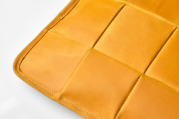 Close-up of mustard yellow leather upholstery showing stitching detail