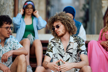 A Multi Ethnic Group of Teenagers Sitting Between Buildings in an Old Mediterranean Tourist City.