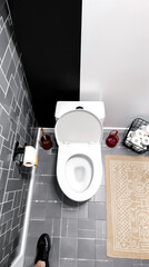 clean white toilet in modern bathroom with grey tiles and beige rug