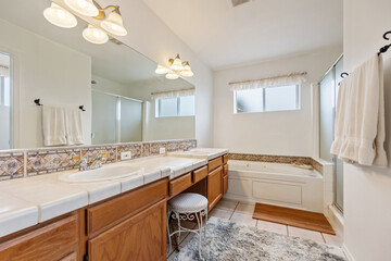 A beautifully designed bathroom with two sinks, a tub, and a mirror