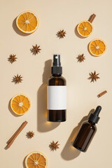 Naklejka premium amber bottles with dried orange and spices on beige background