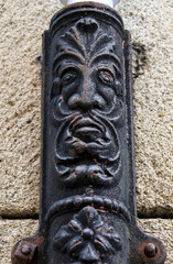 Face on old forged metal gutter in Segovia city