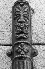 Face on old forged metal gutter in Segovia city