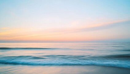 Obraz premium Ocean waves meet the shore under a pastel sky at sunrise or sunset.