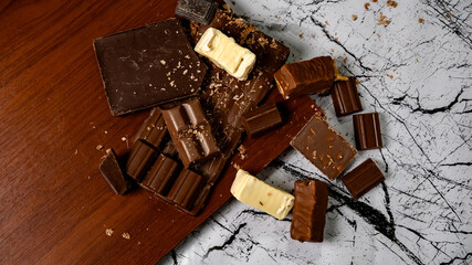 Assorted gourmet chocolate bars on marble and wood background with rich textures