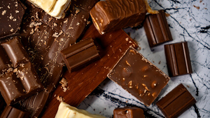 Assorted gourmet chocolate bars on marble and wood background with rich textures