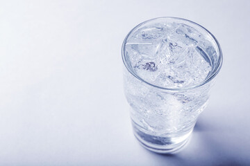 Glass of soda water with ice on light background. Space for text