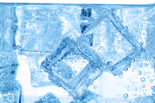 Refreshing soda water with ice cubes as background, closeup