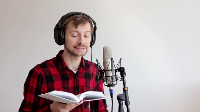 Young man narrator recording audiobook using microphone at recording studio.
