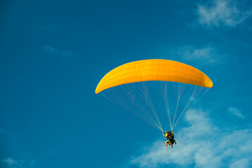 paragliding, yellow parapente on the blue sky.