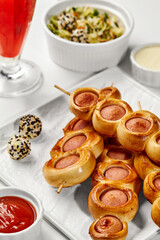Sausage rolls on skewers creating a delicious party snack with dipping sauces