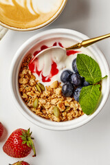 Healthy breakfast with yogurt, granola, berries, and latte art coffee