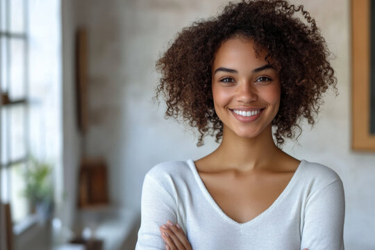 Woman with curly hair smiling in front of a colorful sunset.