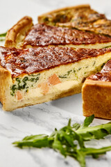 Delicious homemade salmon and spinach quiche resting on a marble surface