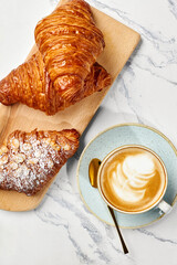 Delicious french croissants and cappuccino resting on marble table