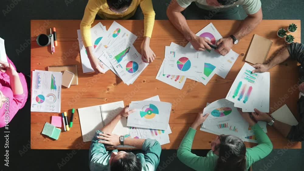 Poster top down view of start up business team holding paper while discussing about financial idea. aerial 