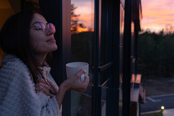 Savoring a warm beverage while relaxing on the balcony, surrounded by the serene beauty of a...