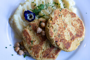 A plate of food with two pieces chickpeas patty