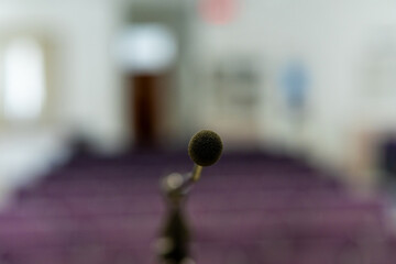 A minimalistic image showing a single microphone slightly out of focus, centered in front of an...